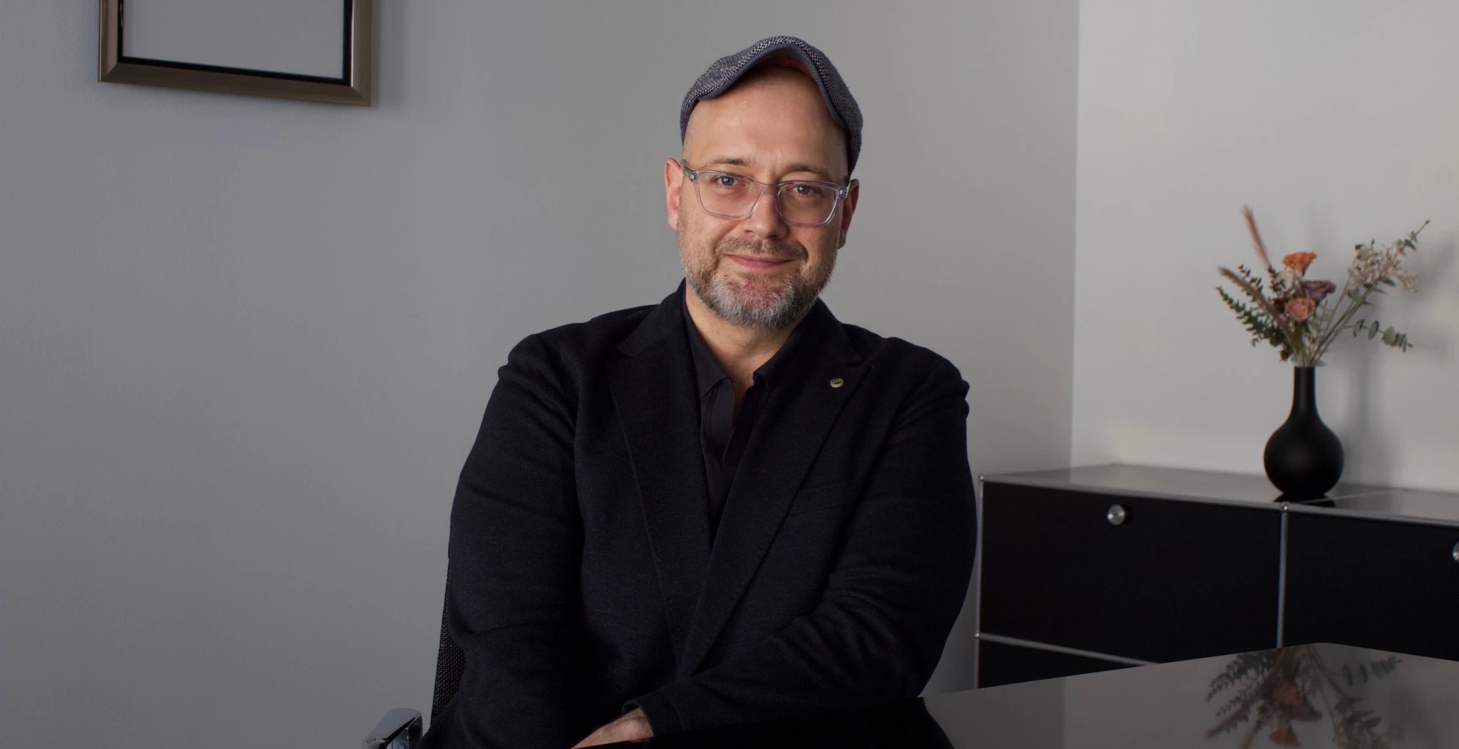 Marco Pape, Fachanwalt für Arbeitsrecht in Frankfurt, sitzt mit Schiebermütze an einem Tisch.